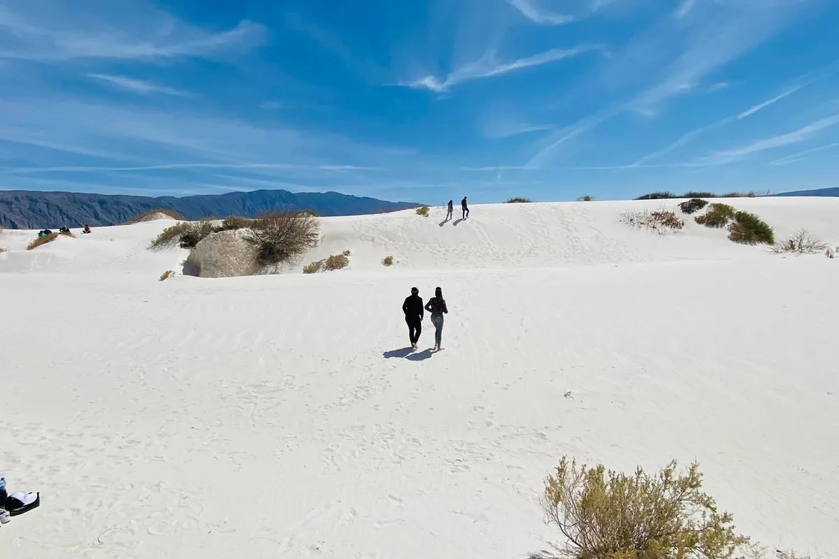 Turistas caminando sobre las Dunas de Yeso blancas de Cuatro Ciénegas, Coahuila, rodeadas de montañas