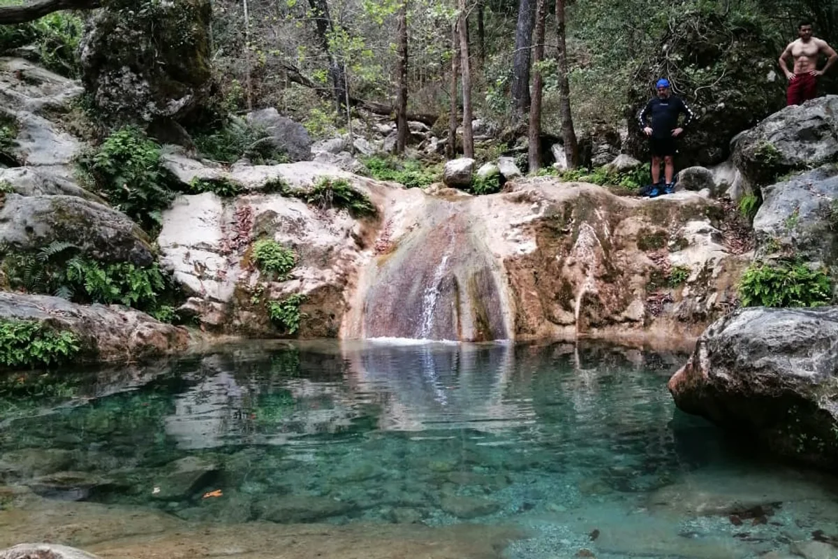 Poza de aguas turquesa y cascada natural rodeada de bosque en La Estanzuela, Santiago